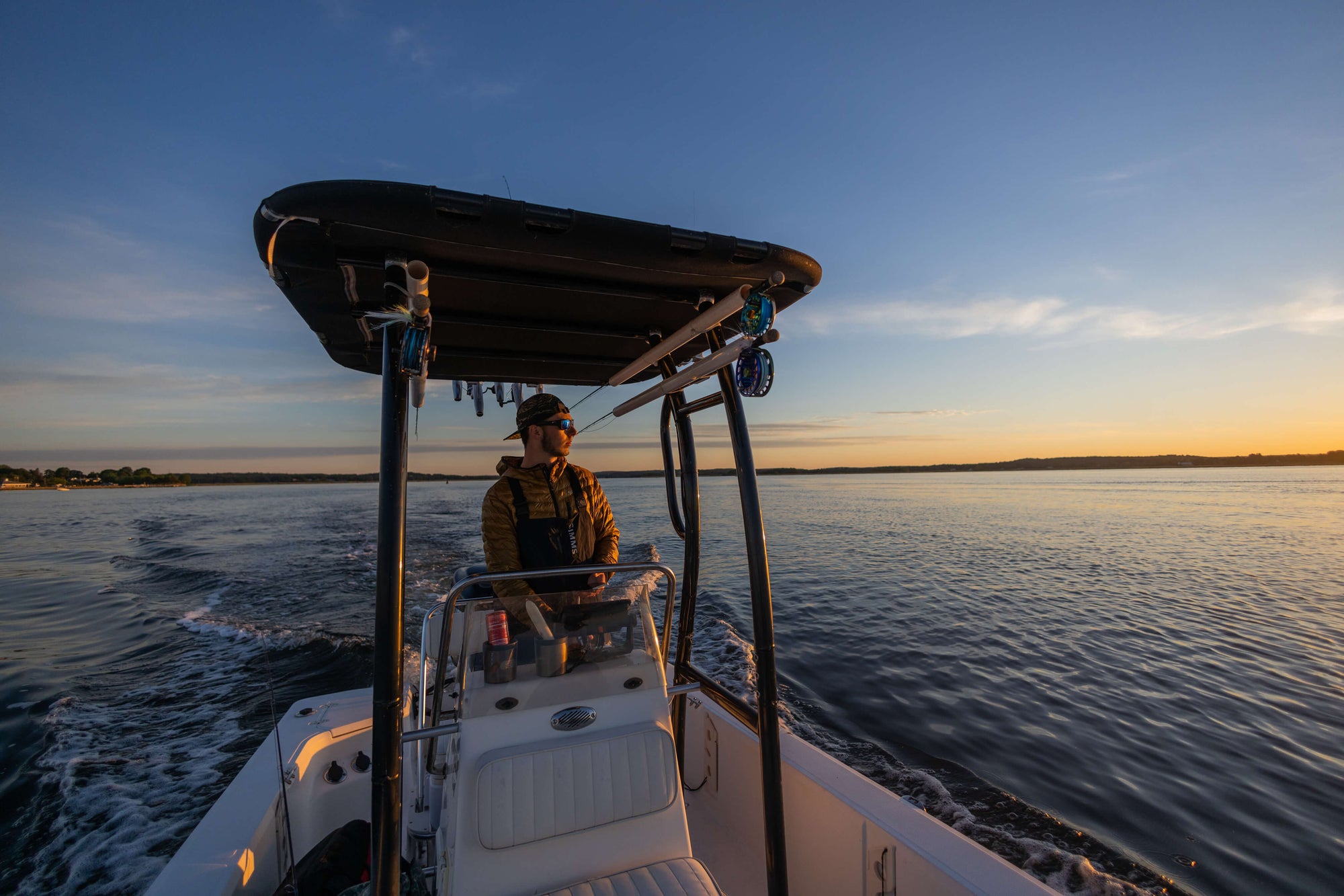 A man standing on his boat, while overlooking the sunset 