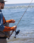 Angler holding onto his fishing pole and his lure is dangling up in the air. 
