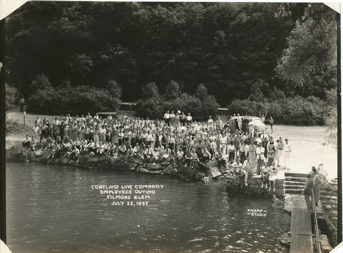 Cortland line employee group of people by a lake with trees in the background in 1937