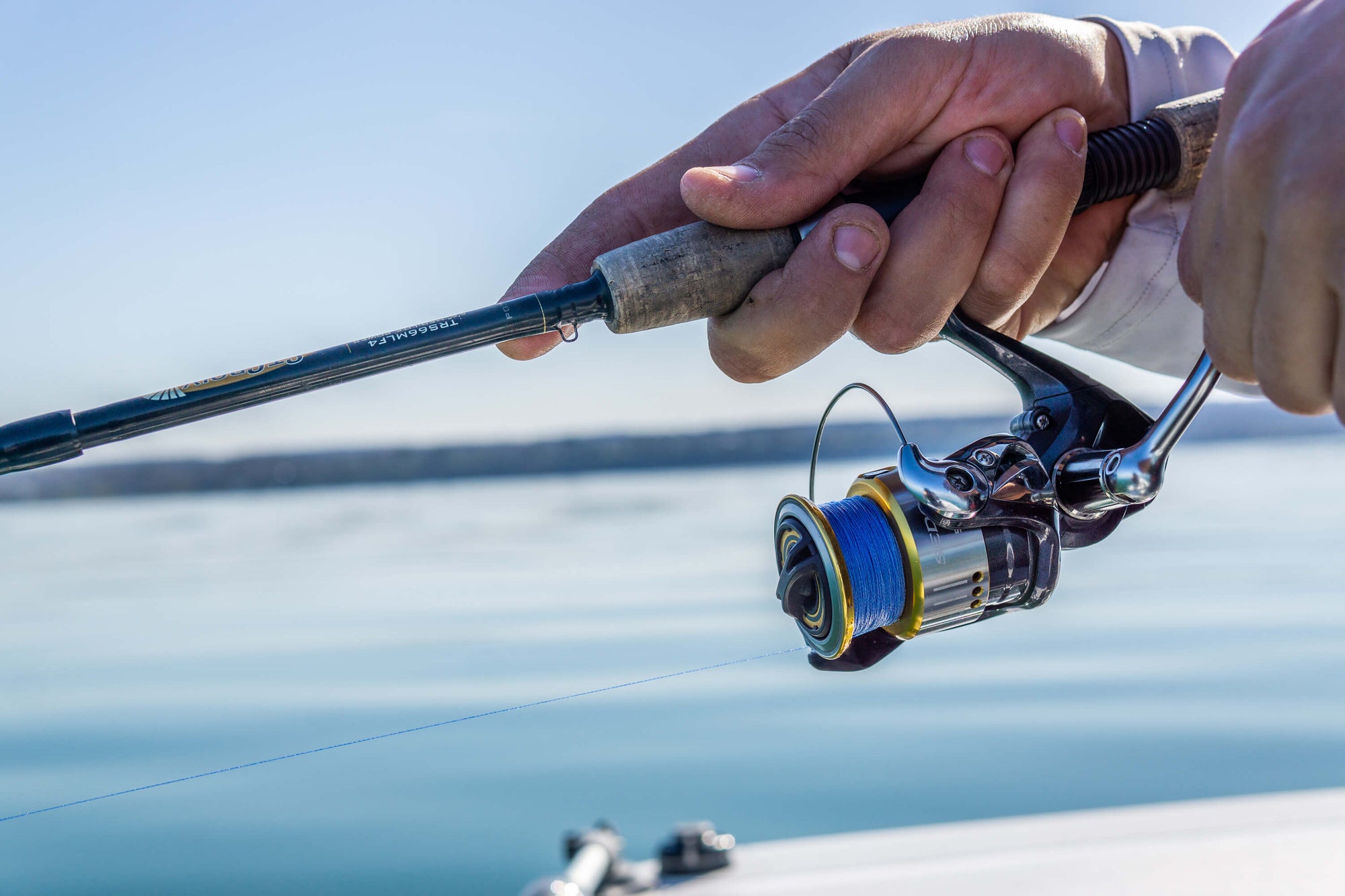 Someone holding onto a fishing pole and it is lined with Cortland Master Braid Blue. 