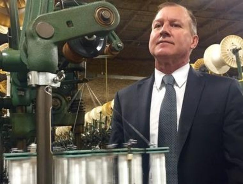Man in a suit standing in front of industrial machinery