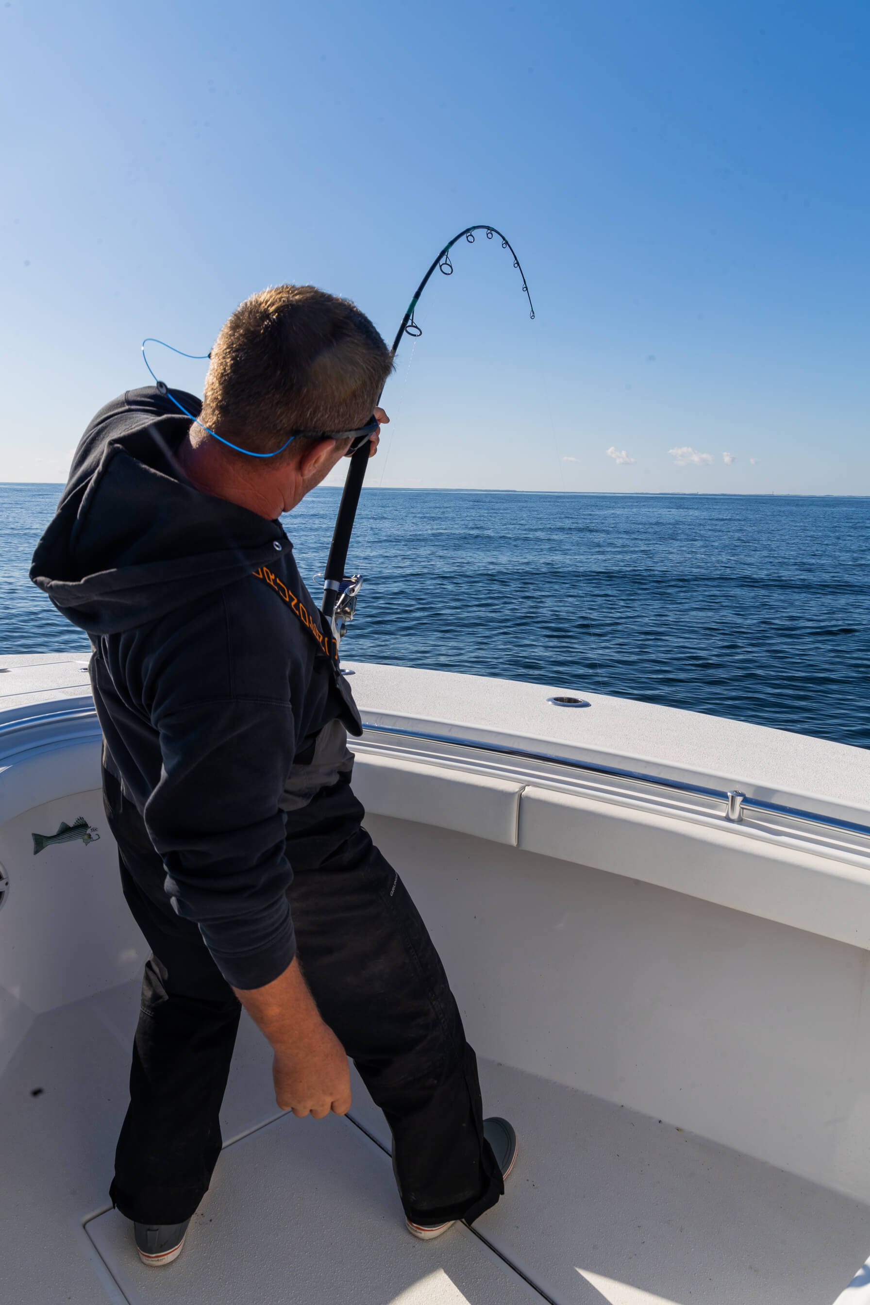 A man is standing on his boat and holding onto his fishing pole