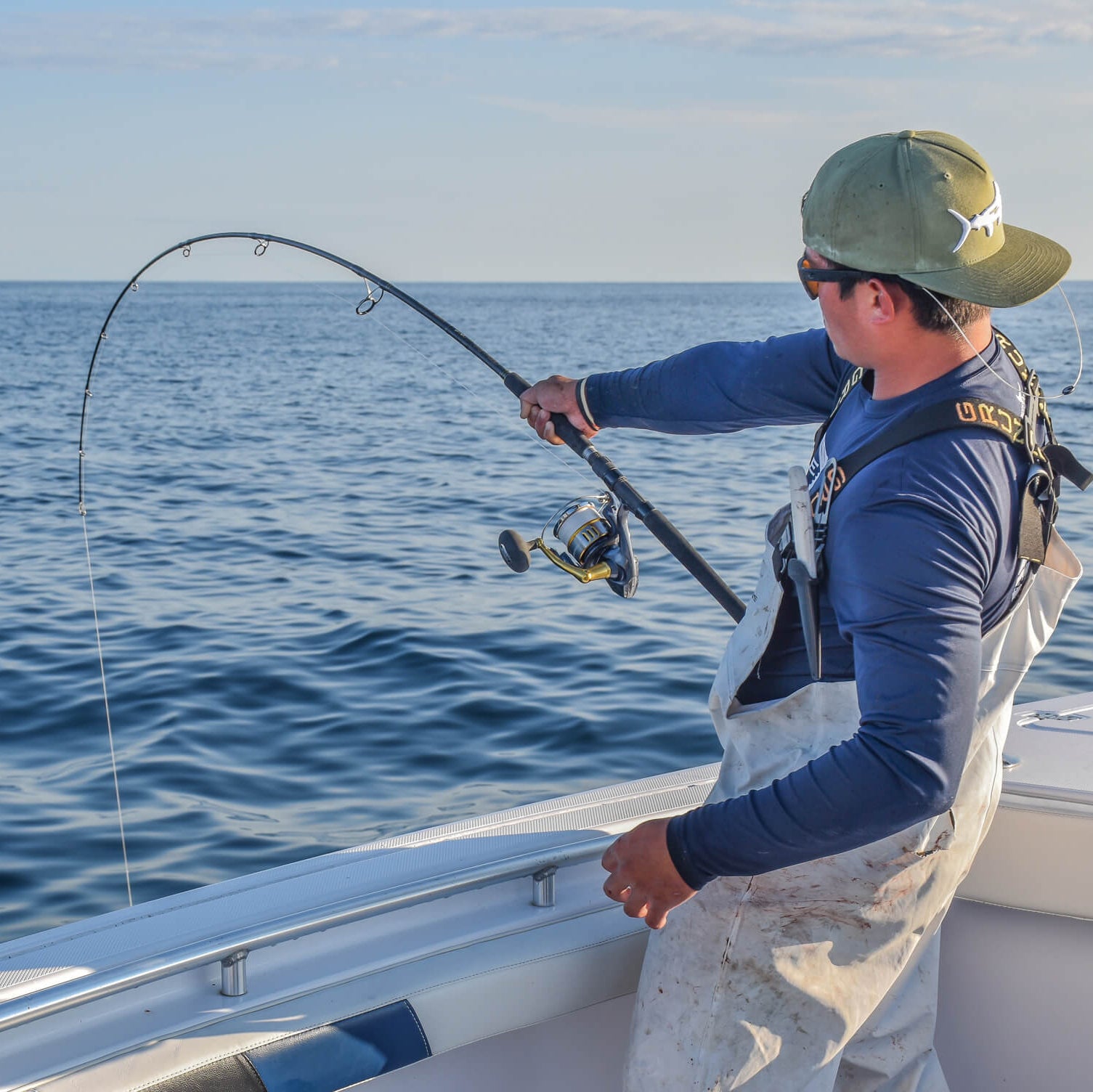 An angler is holding onto his fishing pole, which is bending 