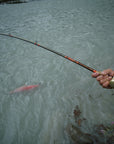 An angler is holding onto their pole and has caught a fish on their line. 