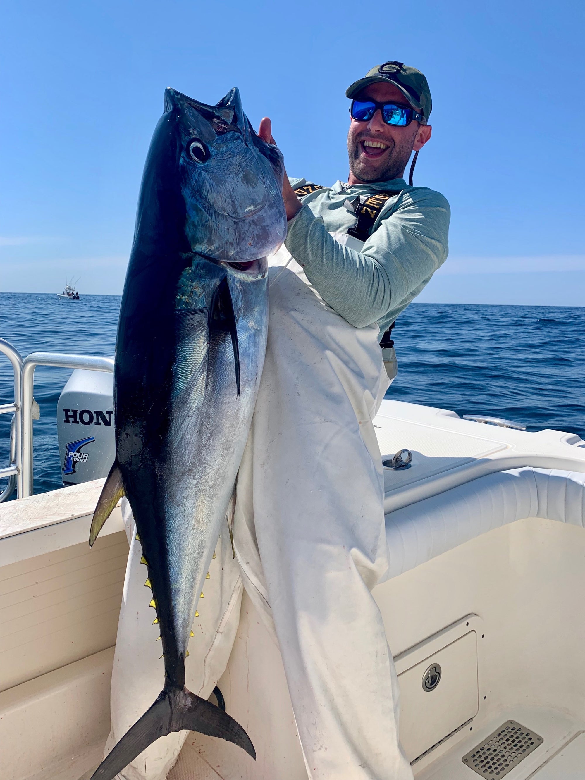 A man is standing on a boat and holding up a large fish. 