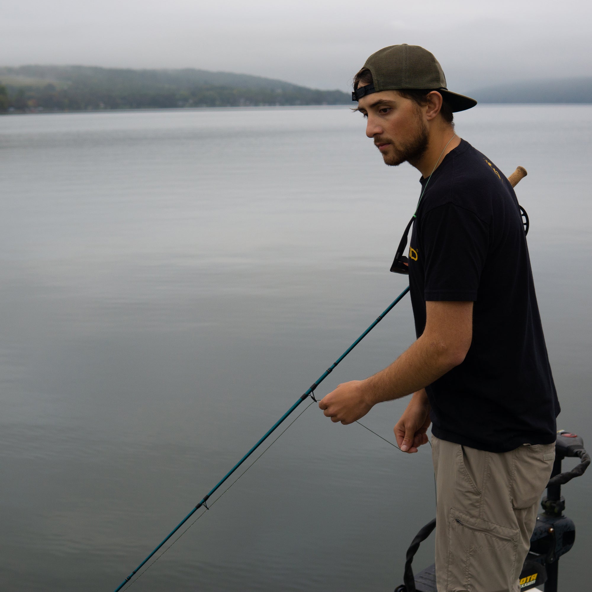 An angler is holding onto his fly rod and onto his line. 