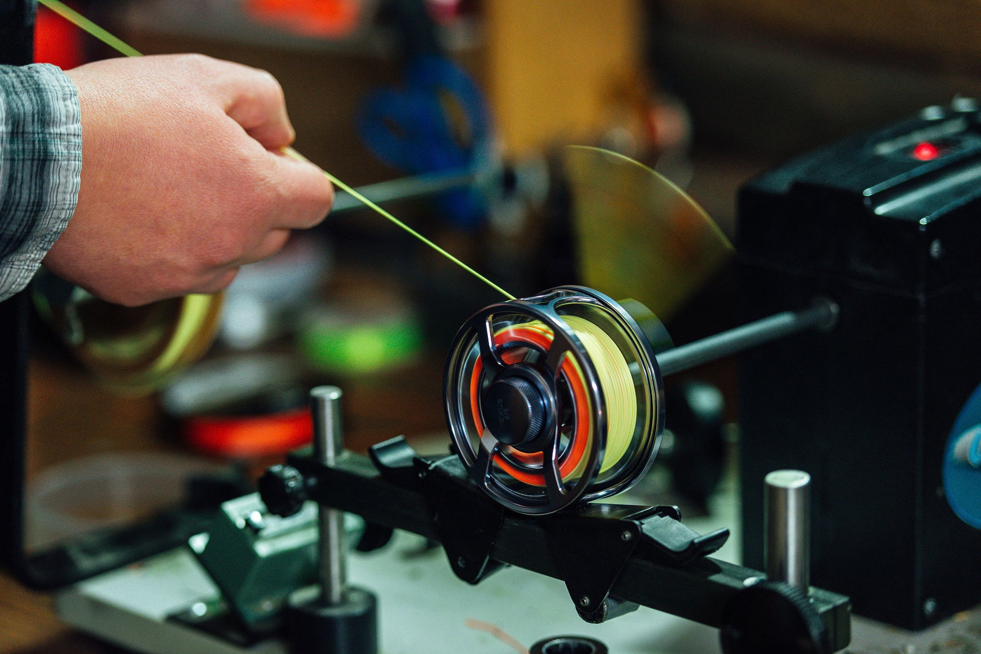 Someone&#39;s hand is lining a fly reel with Chartreuse Micron Fly Line Backing