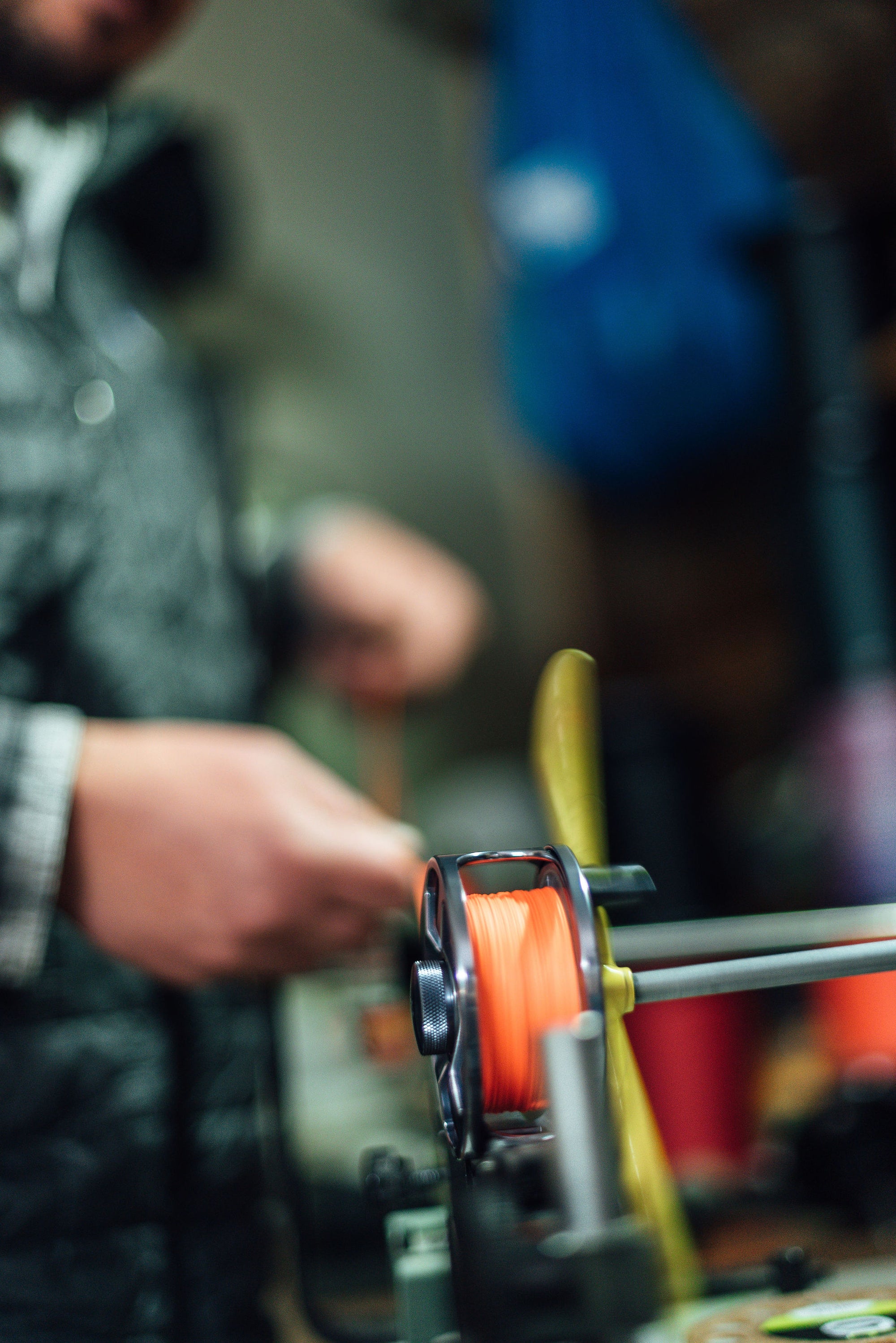 A fisherman is lining their fly reel with Orange Micron Fly Line Backing